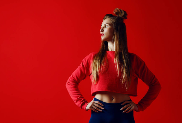 fitness woman in sportswear standing with hands on hips isolated over red background - Photo, image