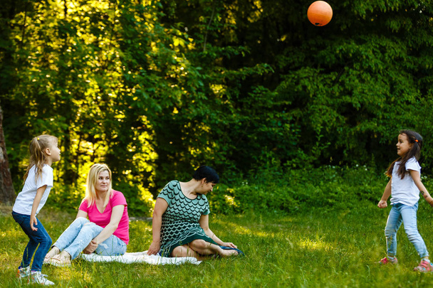 Due madri con figlie in età prescolare che riposano nel parco verde
 - Foto, immagini