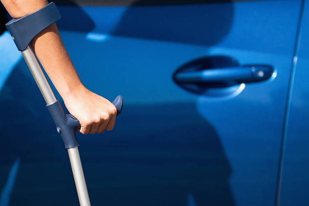 Mujer discapacitada con muletas abriendo la puerta de un coche, viajes y transporte para personas con discapacidad
 - Foto, Imagen