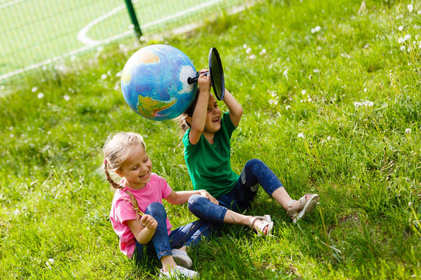 Due piccole studentesse sedute sull'erba con Globe
  - Foto, immagini