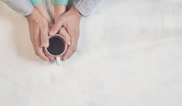 Verliebte Paare halten Händchen mit Kaffee auf weißem Marmortisch. Foto von oben, Ansicht von oben mit Kopierraum - Foto, Bild