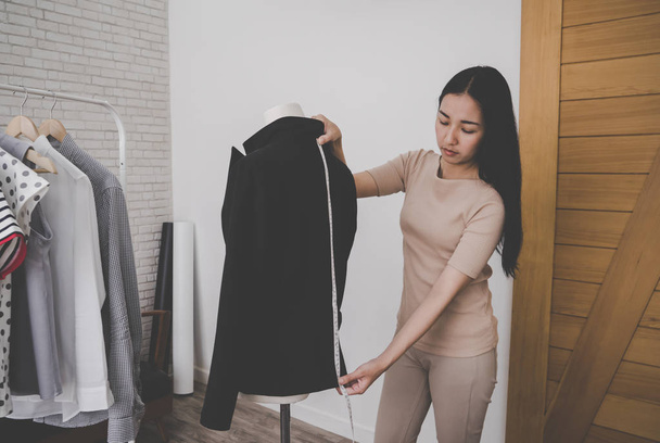 Female fashion designer tailor is measuring office suit jacket - 写真・画像