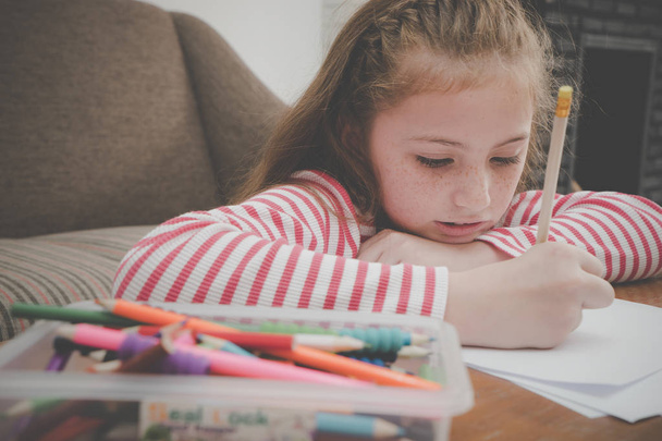 Little girl is coloring on blank paper in living room - Fotografie, Obrázek