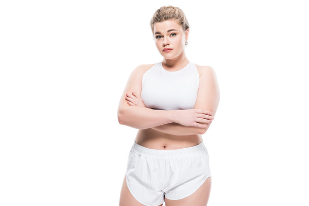 young oversize woman in sportswear standing with crossed arms and looking at camera isolated on white  - Photo, Image