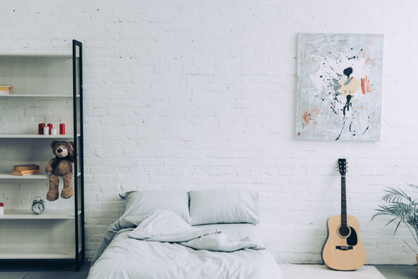 high angle view of modern bedroom with shelves, guitar and painting on white brick wall  - Фото, изображение