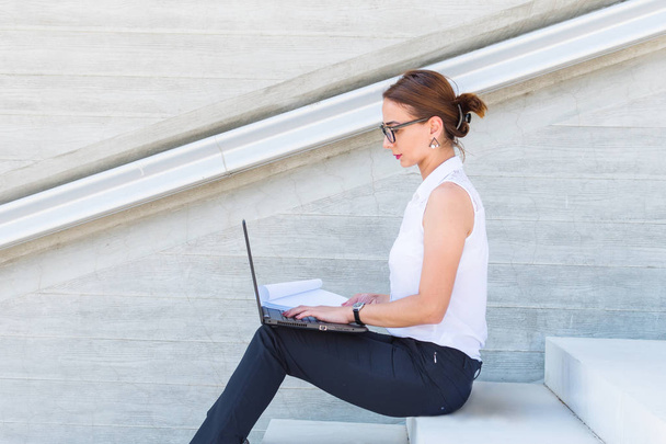 business woman with glasses sitting with laptop on the stairs - Photo, image