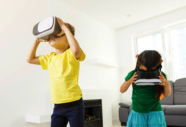 two little girls using virtual reality goggles in living room at home - Foto, afbeelding
