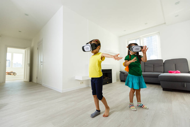 δύο κοριτσάκια χρησιμοποιώντας εικονική πραγματικότητα γυαλιά στο σαλόνι στο σπίτι - Φωτογραφία, εικόνα