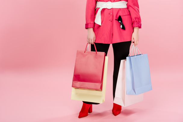 cropped shot of stylish oversize woman holding shopping bags on pink - Foto, Imagen
