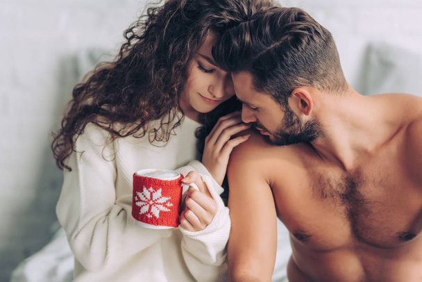 close up view of curly woman holding coffee cup while her boyfriend sitting near  - Фото, зображення