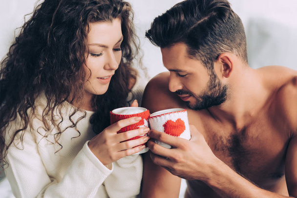 selective focus of couple clinking by coffee cups in woolen cases  - Photo, Image