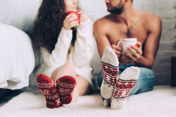 cropped image of couple drinking coffee and wearing colorful socks at home - Valokuva, kuva