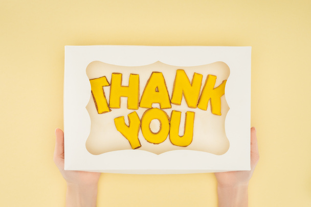 cropped person holding square-shaped cake in box with thank you lettering isolated on yellow background - Foto, immagini