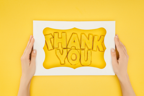abgeschnittene Person mit quadratischer Torte in Schachtel mit Dankeschön-Schriftzug isoliert auf gelbem Hintergrund - Foto, Bild