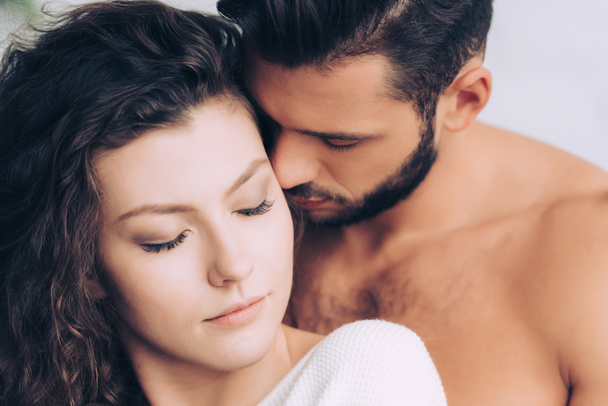handsome man kissing beautiful curly girlfriend posing with closed eyes - Foto, Imagem