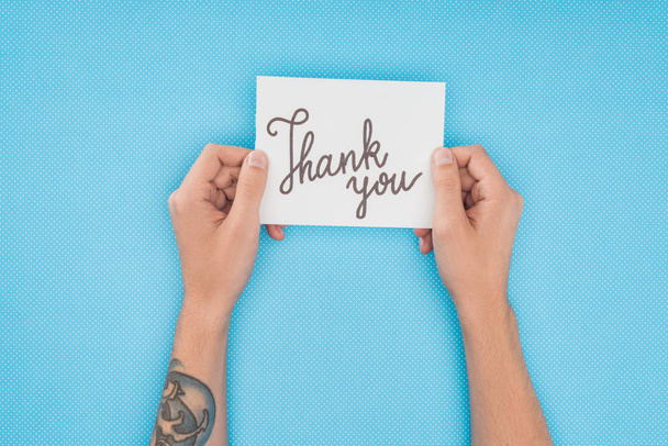 cropped person holding paper with thank you lettering isolated on blue background - Фото, изображение