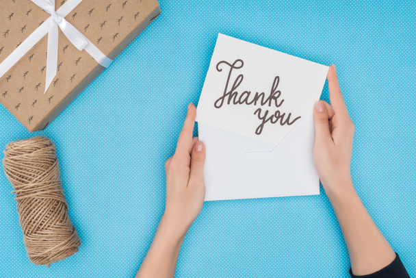 cropped person holding paper with thank you lettering isolated on blue background - Fotografie, Obrázek