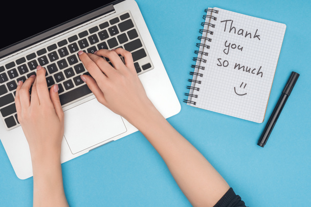 cropped view of woman working on computer and notebook with thank you so much lettering isolated on blue background - Photo, Image