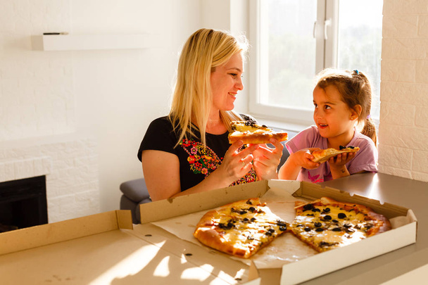 Madre e figlia mangiare pizza in cucina
 - Foto, immagini
