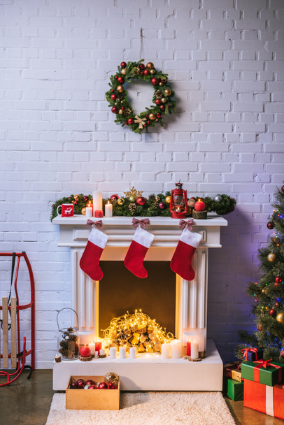 Chimenea con decoraciones cerca del árbol de Navidad en casa
 - Foto, Imagen