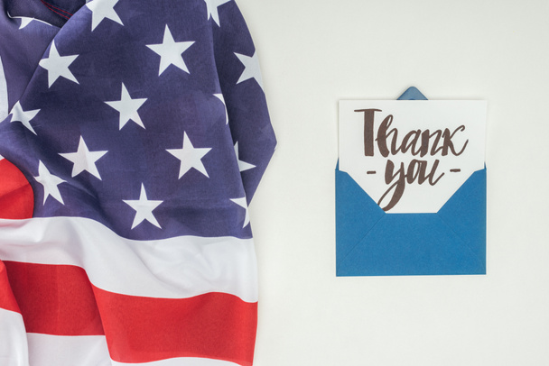 thank you lettering sticking out of blue envelope with american flag isolated on white background - Photo, Image