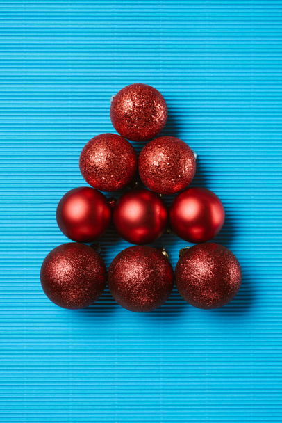 Flat lay of red shiny decorative christmas balls on the blue background - Foto, Imagem