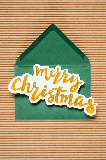 Flat lay of green envelope with yellow Merry Christmas sign   - Foto, Bild