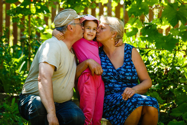 Menina posando com avó e avô no jardim verde
  - Foto, Imagem