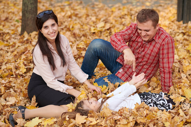 Happy family is in autumn city park. Children and parents. They posing, smiling, playing and having fun. Bright yellow trees. - Foto, immagini