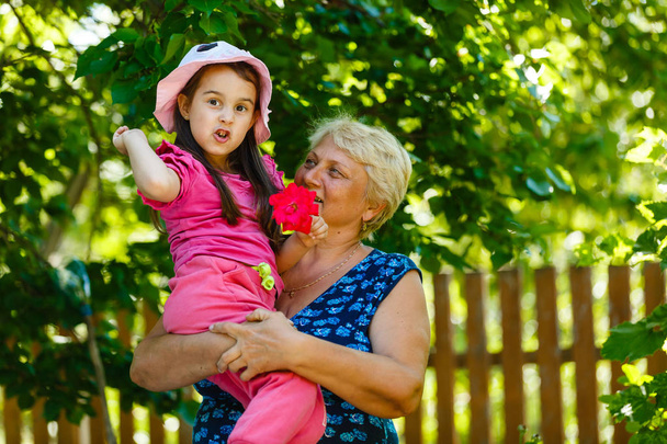 Ευτυχισμένη γιαγιά ποζάρει με μικρό κορίτσι στον κήπο  - Φωτογραφία, εικόνα
