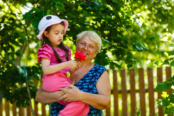 Happy grandmother posing with little girl in garden  - Photo, Image