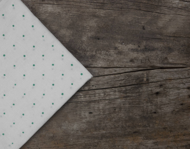 grüne gepunktete Tischdecke oder Handtuch über der leeren Oberfläche eines Holztisches. Ansicht von oben - Foto, Bild