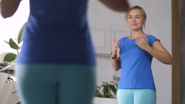 Smiling woman satisfied with body shape in mirror - Záběry, video