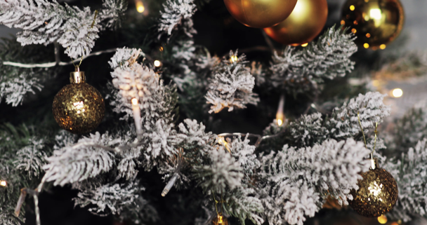 Χαιρετισμός σεζόν έννοια. Κουκλίτσα της στολίδια για το χριστουγεννιάτικο δέντρο με διακοσμητικά φως και χιόνι που υπάγονται - Πλάνα, βίντεο