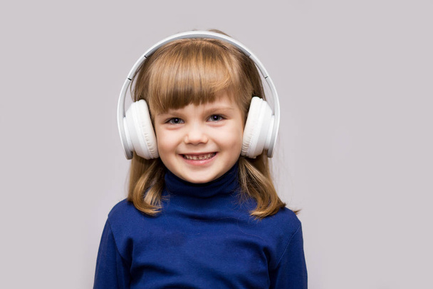 Onnellinen hymyilevä lapsi nauttii kuuntelee musiikkia kuulokkeissa valkoisella taustalla
 - Valokuva, kuva