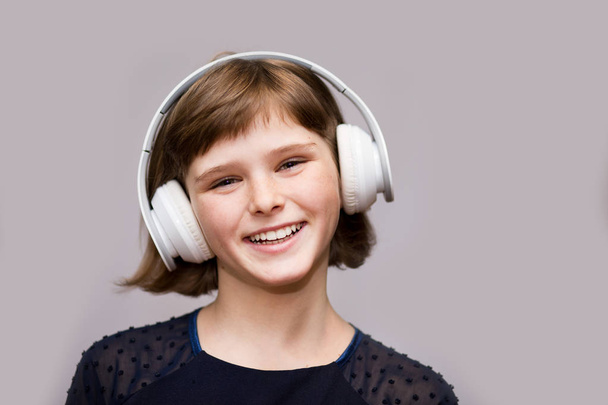 Gelukkig lachend kind luistert naar muziek in hoofdtelefoon geniet op witte achtergrond - Foto, afbeelding