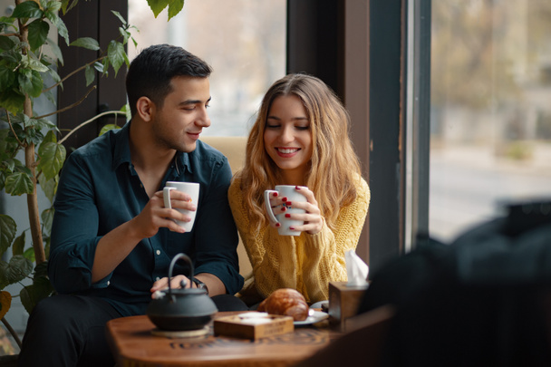 Young attractive couple on date in coffee shop. In love man and woman sitting in a cafe, drinking coffee - Foto, imagen