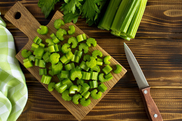 Nasekaný čerstvý celer na prkénku na hnědé dřevěné pozadí. Pohled shora. - Fotografie, Obrázek