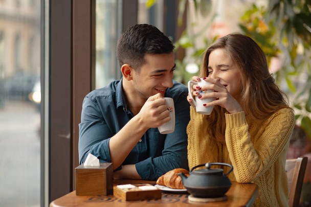 Young attractive couple on date in coffee shop. In love man and woman sitting in a cafe, drinking coffee - Photo, Image