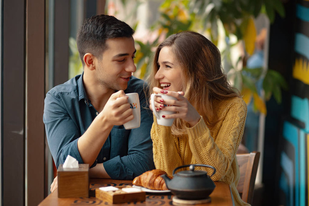 Joven pareja atractiva en la fecha en la cafetería tener una conversación y disfrutar del tiempo pasado juntos
.  - Foto, Imagen