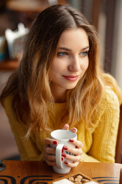 Genç Sevimli Kadın yalnız serbest zaman sırasında bir kafede otururken çok ciddiyim. Portre çekici Bayan kafede istirahat ederken sevimli bir gülümseme ile. - Fotoğraf, Görsel