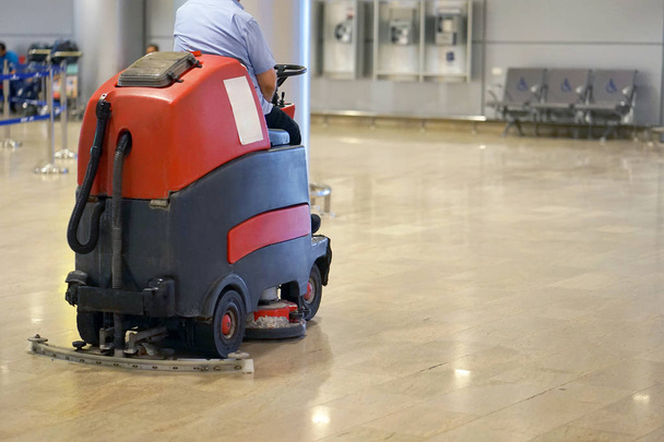 Hombre conduciendo máquina profesional de limpieza de pisos en el aeropuerto o estación de tren o supermercado. Servicio de limpieza y cuidado de suelos
 - Foto, Imagen
