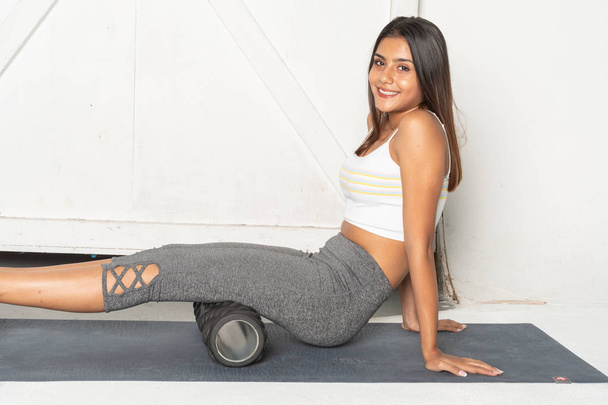 Teenage girl working out in her gym with a foam roller - Zdjęcie, obraz