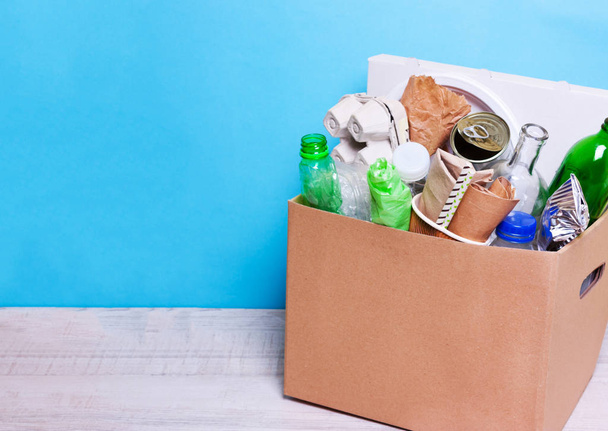 In a cardboard box plastic, glass bottles, cans, paper. The concept of separate sorting of garbage, environmental protection, ecology, recycling household waste - Fotoğraf, Görsel