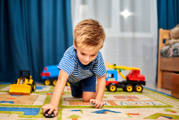 little boy playing with toys on carpet at home - Фото, изображение