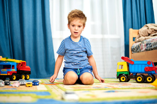 自宅のカーペットにおもちゃで遊んでの小さな男の子 - 写真・画像