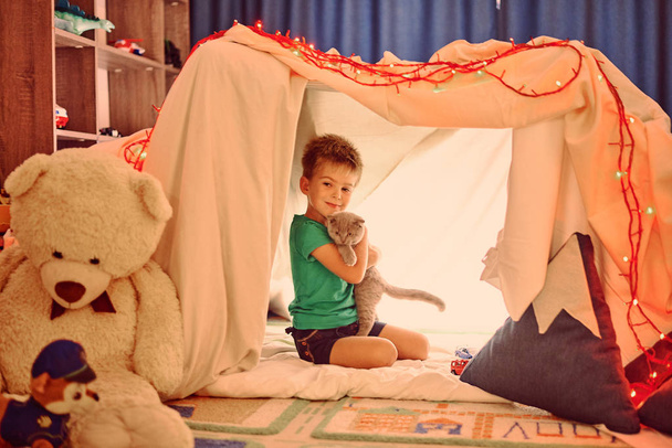 little  boy playing with cat in tent - Фото, зображення