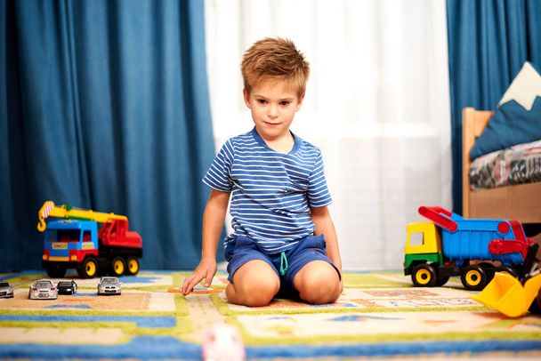 自宅のカーペットにおもちゃで遊んでの小さな男の子 - 写真・画像