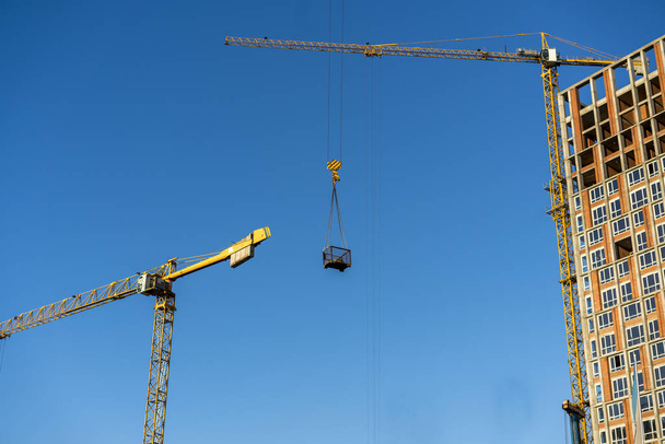 High-altitude crane lifts cargo, against the blue sky. - Photo, Image