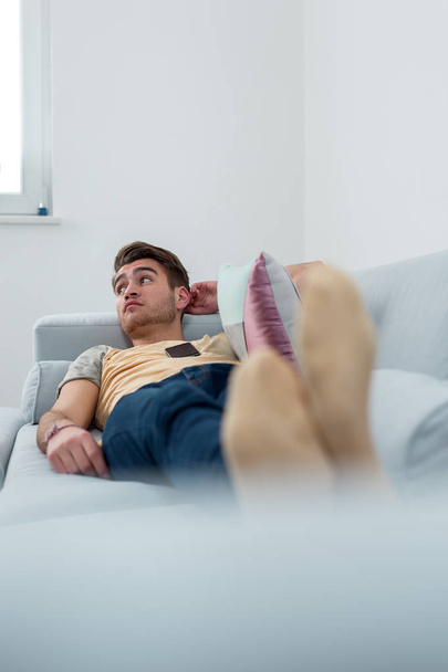 Relaxed man resting lying on a couch in living room - Foto, Imagen